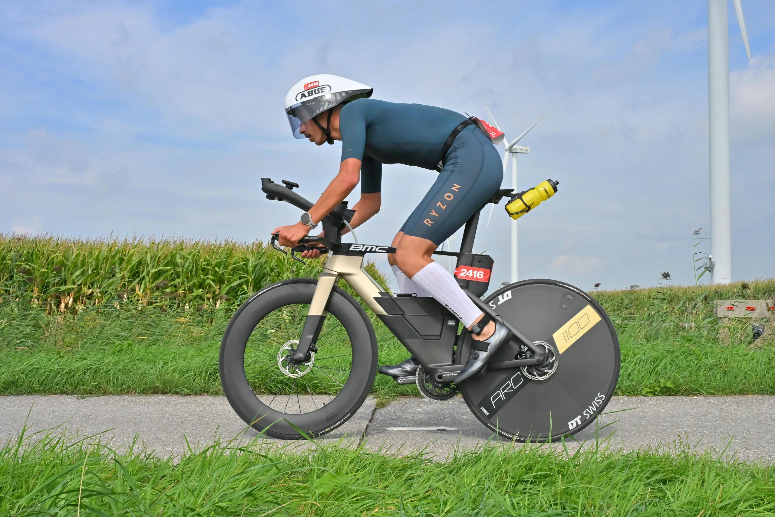Marwan Ghannoudi en position aérodynamique sur son BMC doré au Challenge Almere-Amsterdam, éoliennes en arrière-plan